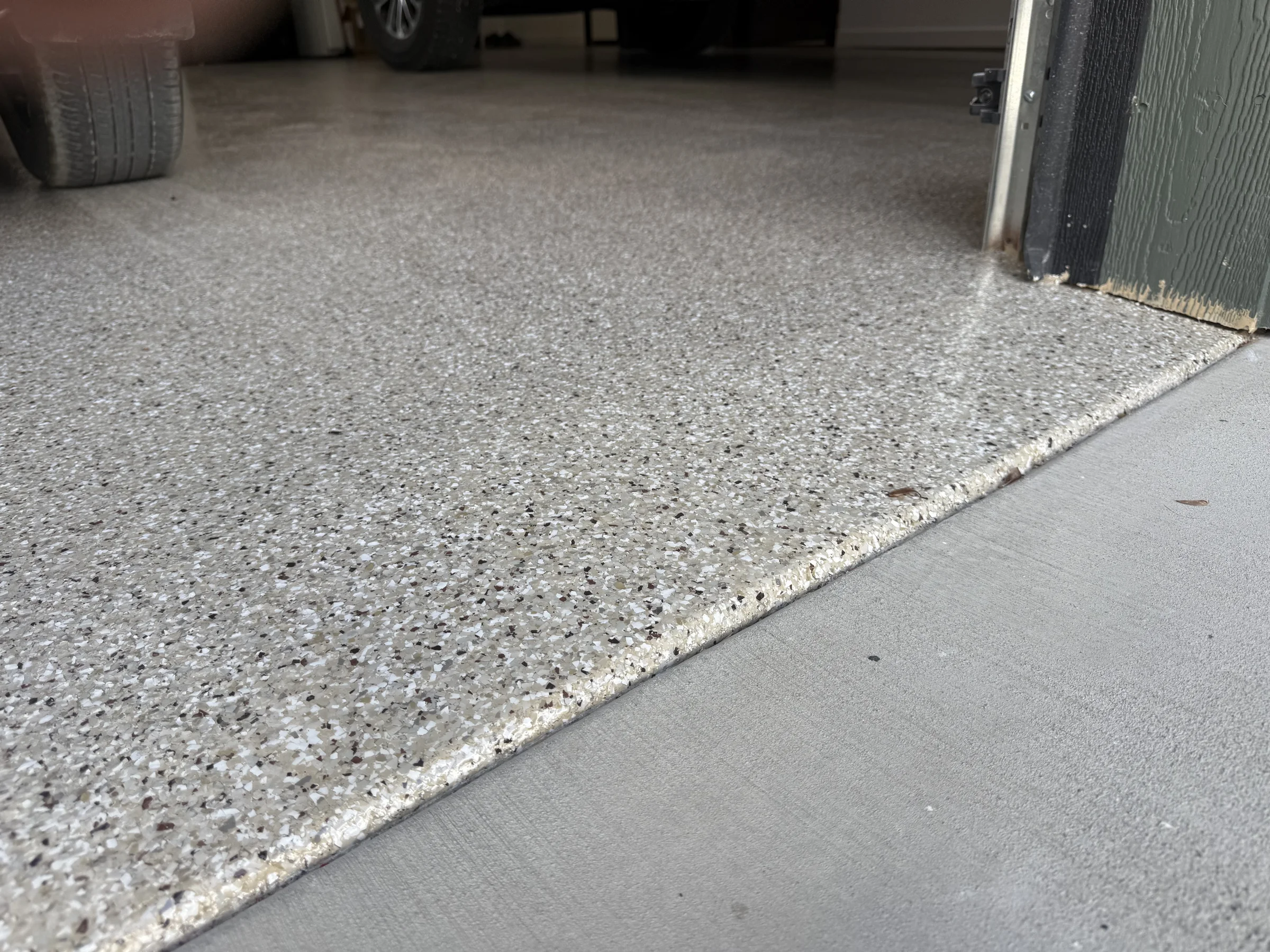 Detail of the edge where finished gray flake epoxy meets bare concrete
